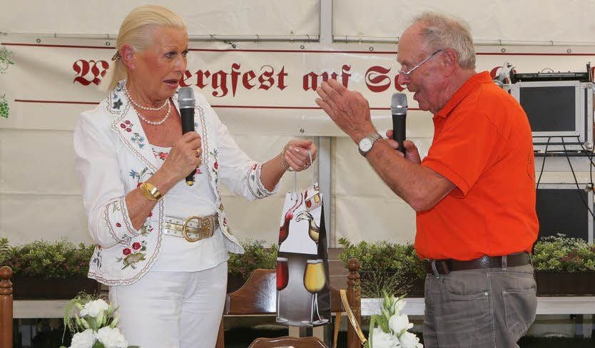 Hans-Jürgen Schiedt überreicht Margitta Lüder-Preil einen Wein .