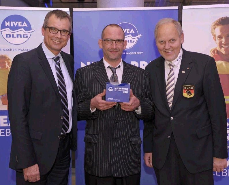 DLRG-Präsident, Hans-Hubert Hatje (r.) und Beiersdorf Markenvorstand, Ralph Gusko (l.) mit dem Preisträger, Tom Süße