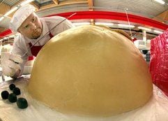 An der größten Mozart-Kugel der Welt, die aus zwei Teilen besteht, arbeitet der Konditormeister Torsten Riel in der Halloren Schokoladenfabrik AG in Halle. (Foto: dpa)