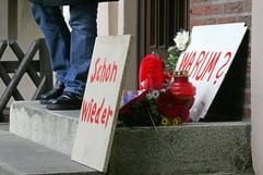 Zwei Schilder mit den Aufschriften «Warum?» und «Schon wieder» stehen am Mittwoch (11.10.2006) zusammen mit einigen Kerzen und Blumen vor dem Hauseingang des Wohnblocks im Stadtteil Gröpelingen von Bremen, in dem am Vortag ein zweieinhalb Jahre alter Junge tot aufgefunden wurde. (Foto: dpa)