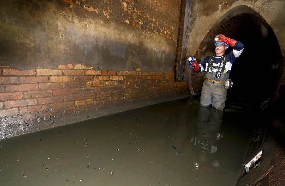 Mario Rehnig muss vorsichtig durch das 70 Zentimeter hohe Abwasser waten, um den Kanal zu kontrollieren.