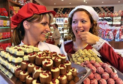 Mit einer Auswahl handgefertigter Pralinen präsentieren sich das Halloren-Schokoladenmädchen Juliane Lieball (rechts) und Chocolatier Claudia Heimann am Donnerstag zur Eröffnung der Halloren Schokoladenwelt in Leipzig. (FOTO: DPA)
