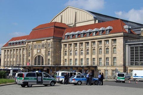 Einsatzkräfte der Polizei stehen am Samstag auf dem ansonsten leeren Vorplatz des Hauptbahnhofes in Leipzig. (FOTO: DPA)