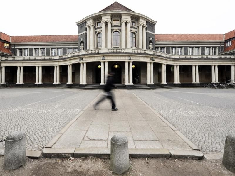 Auf dem Uni-Campus geht ein Passant an dem Universitäts-Hauptgebäude vorbei. Foto: Maurizio Gambarini/dpa