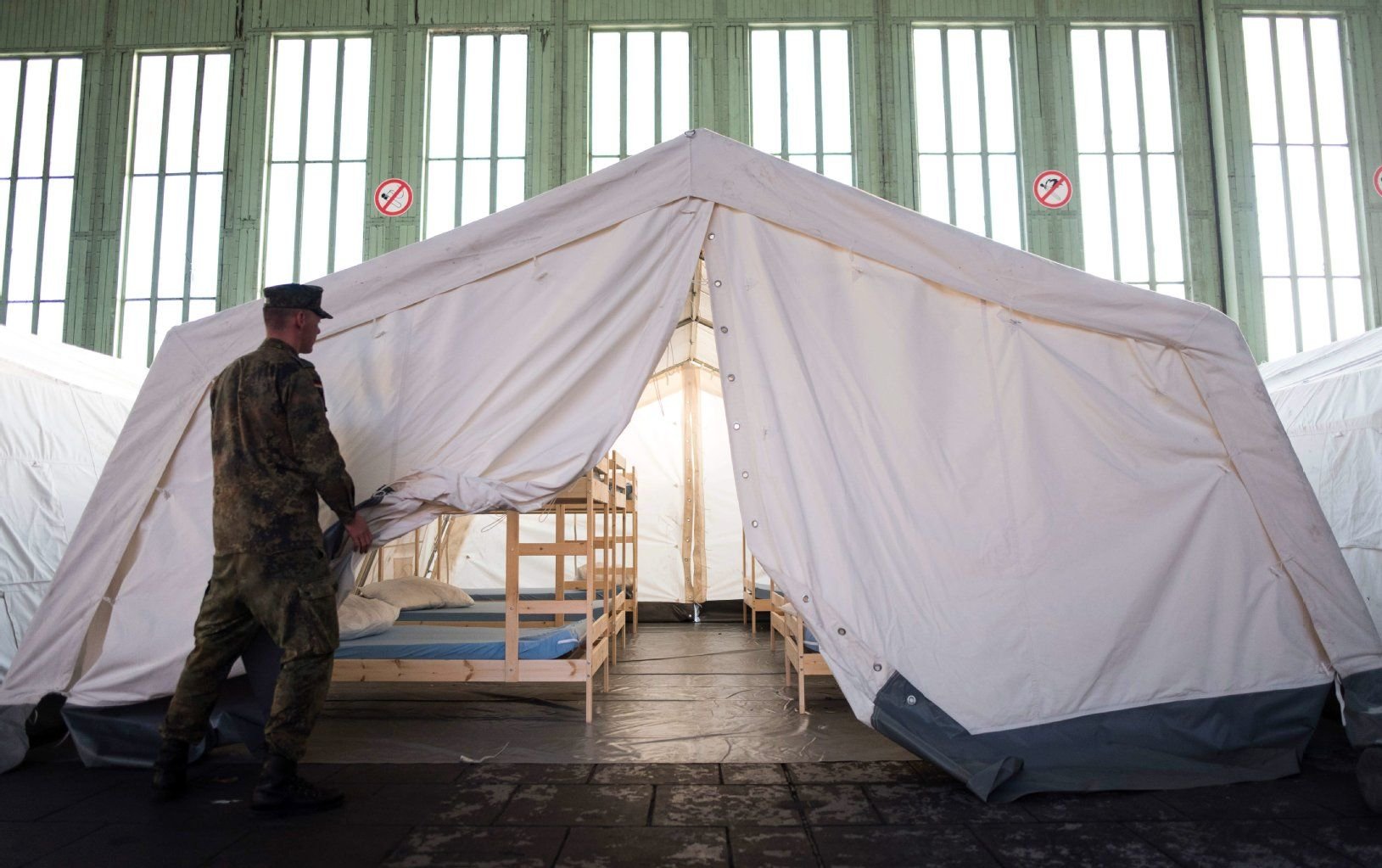 Bundeswehrsoldaten stellen in einem Hangar des Flughafen Tempelhof Zelte auf.