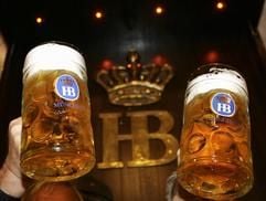 Zwei Männer halten in München vor dem Logo des Münchner Hofbräuhauses Bierkrüge hoch. (Foto: ddp)