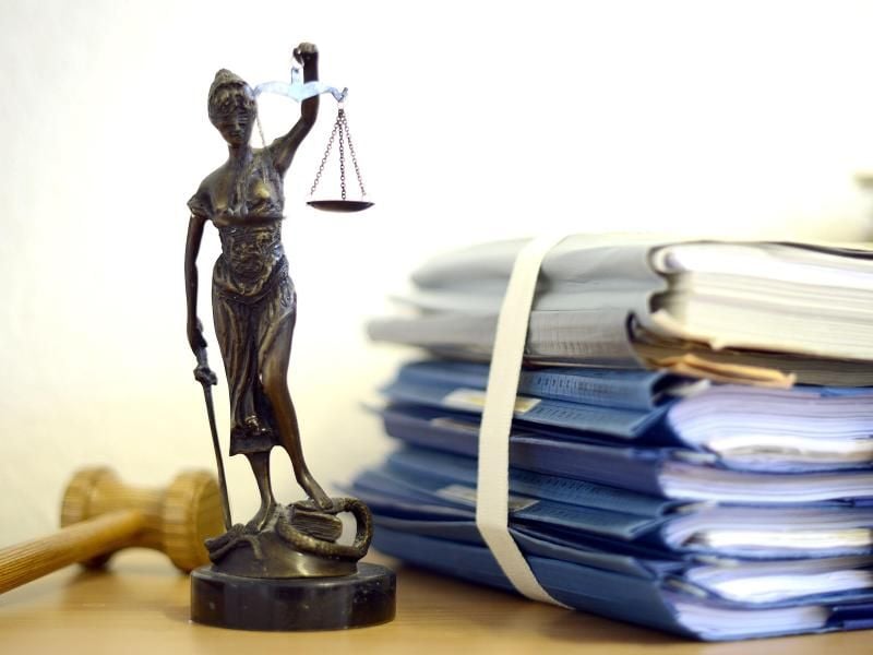 Die Nachbildung der Justitia steht neben einem Holzhammer und Akten. Foto: V. Hartmann/Archiv