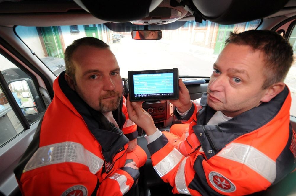 Sascha Wehlert (links) und Sven Köhler, die Besatzung eines der Rettungswagen, mit dem Tablet, auf dem sie ihren Einsatzalarm erhalten.