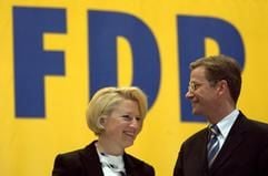 Der FDP-Vorsitzende Guido Westerwelle und die Landesvorsitzende und FDP-Generalsekretärin Cornelia Pieper unterhalten sich am 12. April 2003 beim Landesparteitag der FDP von Sachsen-Anhalt in Halle/Saale vor einem großen Logo der Partei (Archivfoto: dpa)