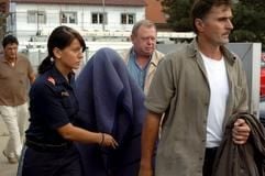 Eine Frau (M), die mutmaßlich die lange vermisste Natascha Kampusch ist, wird am Mittwoch (23.08.2006) in Strasshof in Österreich von Polizisten unter einer Decke fortgeführt. (Foto: dpa)