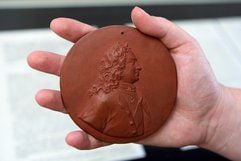 Im Schlossmuseum in Gotha zeigt eine Kuratorin eine Porträtplakette mit dem Abbild von Zar Peter dem Großen aus rotem Böttger-Steinzeug aus Meißen um 1712/13. (Foto: dpa)