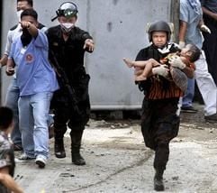 Nach der Erstürmung des Hochsicherheitsgefängnisses in Taguig, einer südlichen Vorstadt der Hauptstadt Manila, bringt ein Polizist ein verletztes Kleinkind zu einem Arzt. (Foto: dpa)