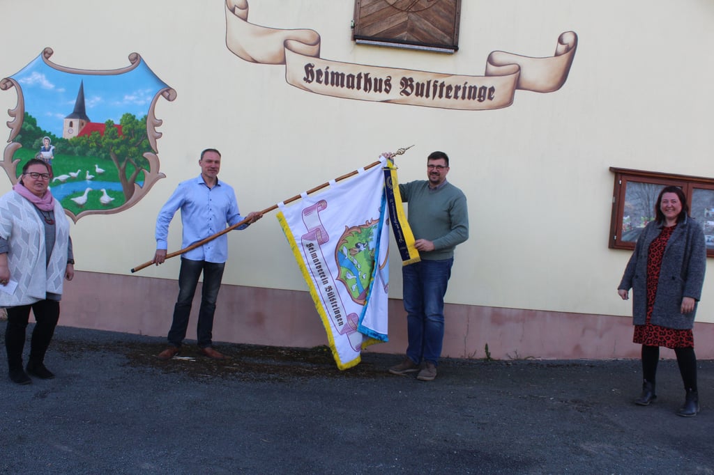 Bürgermeister Sven Fahrenfeld überreicht eine Ehrenschleife zum 15-jährigen Bestehen des Freizeit- und Heimatvereins Bülstringen.