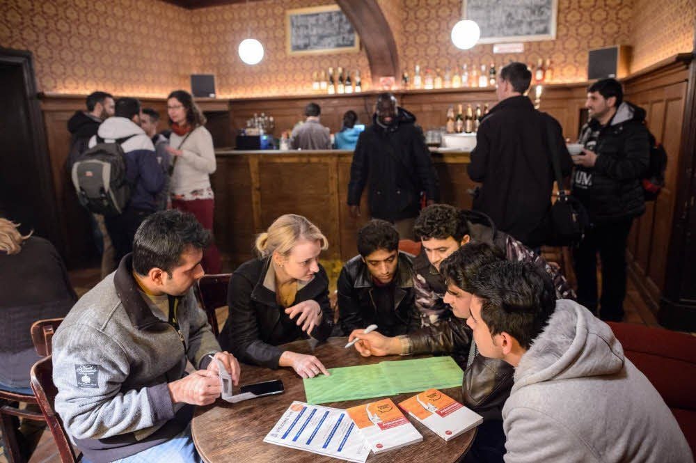 Mitorganisatorin Bettina Hötzel erklärt Flüchtlingen, wo sie Deutschkurse belegen können.