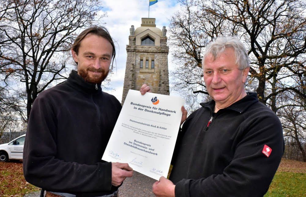 Daniel Kittler (l.) und Wolfgang Kloß zeigen vor dem Bismarckturm die Urkunde, die sie als Träger des Bundespreises erhalten haben.