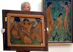 Ein Museumsmitarbeiter trägt am Donnerstag (03.07.2003) im Museum Folkwang in Essen das Bild "Badende am Waldsee" (1919 - auf der Vorderseite, nicht im Bild) des Expressionisten Otto Mueller (1874-1930), dessen Rückseite (hier: vorne) ein bis dahin unbekanntes Motiv aus dem Jahr 1913 zeigt. Rechts das Bild "Knabe vor zwei stehenden und einem sitzenden Mädchen" (1918). Das Museum Folkwang zeigt vom 04.07.2003 bis 28.09.2003 unter dem Titel "Otto Mueller. Eine Retrospektive" insgesamt 54 Gemälde, 25 Zeichnungen und Aquarelle sowie 33 handkolorierte Lithographien. (Foto: dpa)