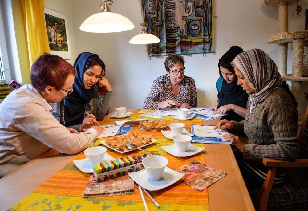 Annette Hanitzsch (links) und Irmgard Helsper (Mitte) üben mit Najma, Soghra und Zarghone am heimischen Küchentisch Deutsch.