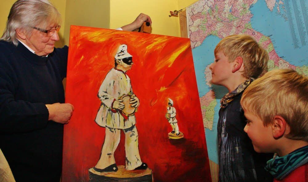 Ingolf Zeise zeigt Aaron und Damian ein Bild von der Figur Pulcinella.
