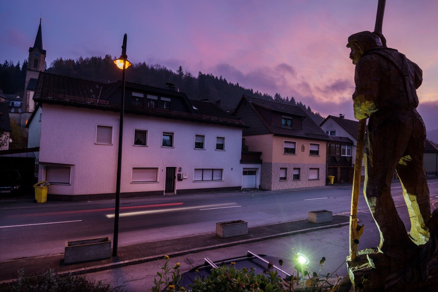 Ein geschnitzter Flößer steht am in Wallenfels neben dem Haus, in dem die Polizei am Vortag sterbliche Überreste von Säuglingen gefunden hat.