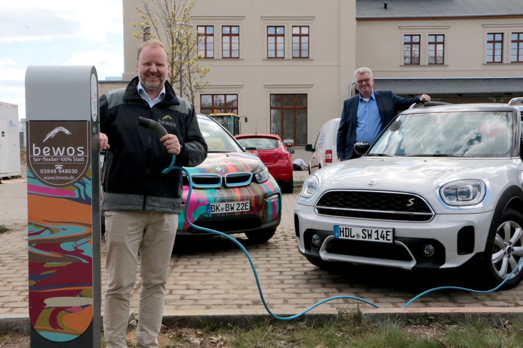 Thomas Harborth von der Bewos (links) und Detlef Koch von den Stadtwerken Haldensleben mit zwei E-Autos und der neuen Ladesäule.