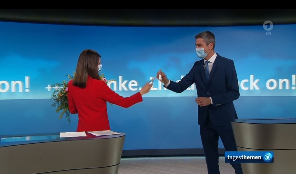 Das Standbild der "Tagesthemen"-Sendung vom 26.04.2021 zeigt Moderatorin Linda Zervakis , die "Tagesthemen"-Moderator Ingo Zamperoni in ihrer letzten Sendung mit einem Ouzo verabschiedet.