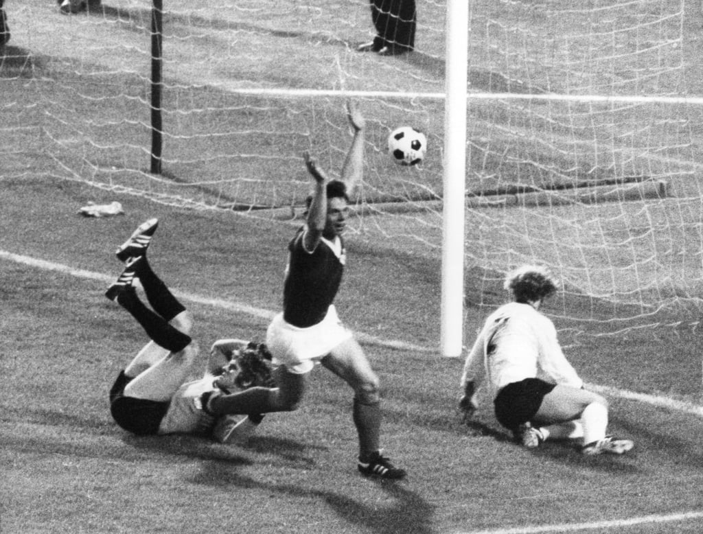 Jürgen Sparwasser (M) von der Fußball-Nationalmannschaft der DDR jubelt am 22.06.1974 im Hamburger Volksparkstadion nach seinem Treffer zum 1:0 gegen die Bundesrepublik Deutschland mit erhobenen Armen, der geschlagene westdeutsche Torhüter Sepp Maier (l) und Verteidiger Berti Vogts (r) liegen geschlagen. Das Tor in der 78. Spielminute bedeutete gleichzeitig den Endstand im Weltmeisterschafts-Finalrundenspiel. dpa (nur s/w - zu dpa-Korr.-Bericht: "Sparwasser: 'Das Tor hat mir geschadet' - Beckenbauer: 'Sonst nie Weltmeister geworden'" am 21.06.1999) +++ dpa-Bildfunk +++