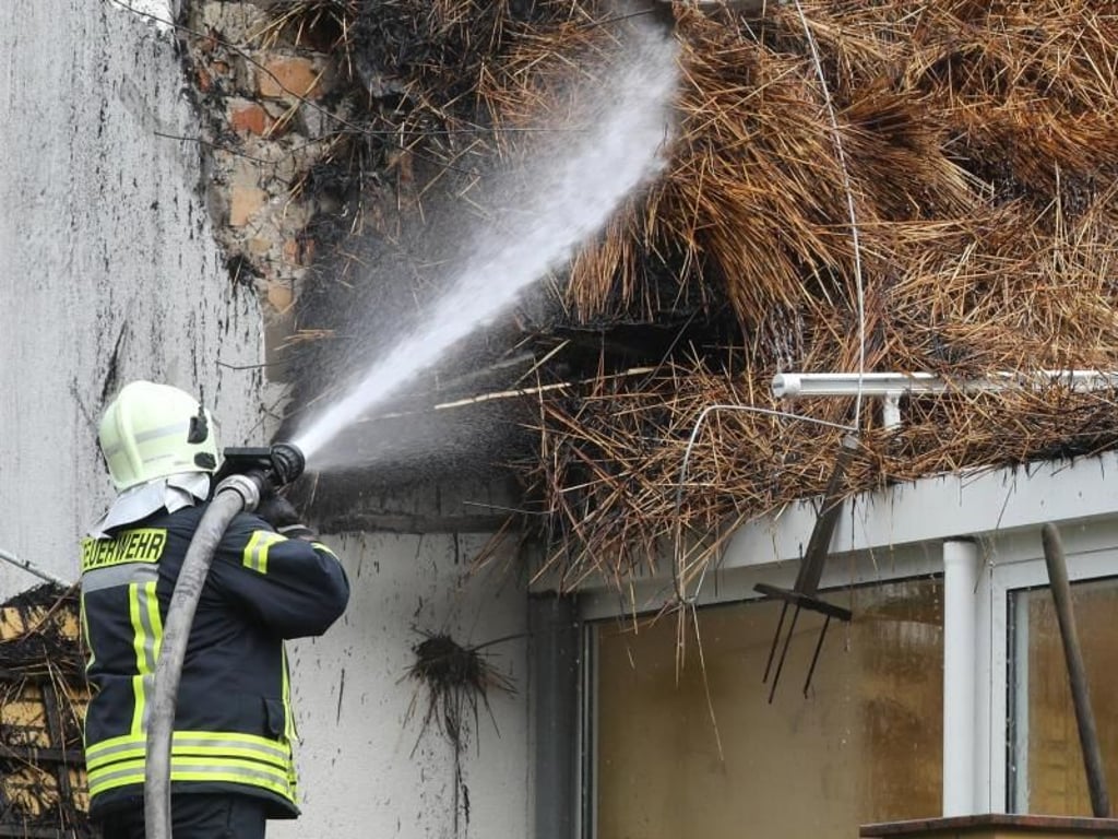 Ein Feuerwehrmann löscht Glutnester im Dachstuhl des ausgebrannten Ostseehotels. Foto: Bernd Wüstneck/dpa-Zentralbild