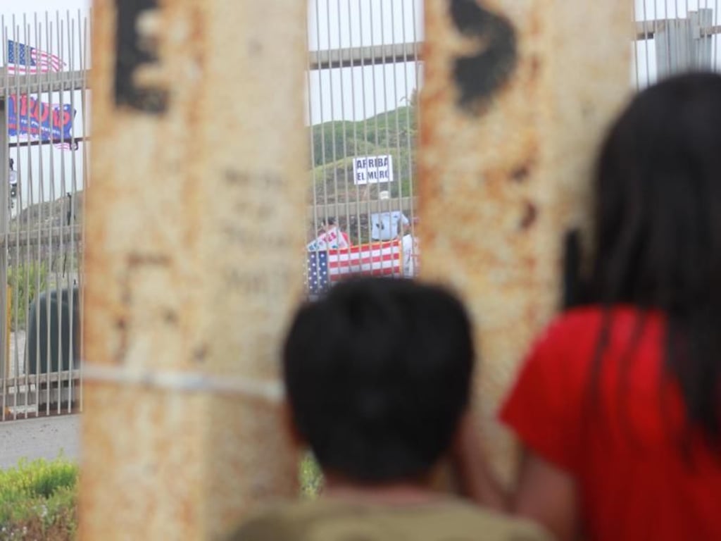 Blick nach drüben: Mexikanische Kinder beobachten durch den Grenzzaun Trump-Anhänger, die eine Verstärkung der Mauer fordern. Foto: Luis Angel Garcia