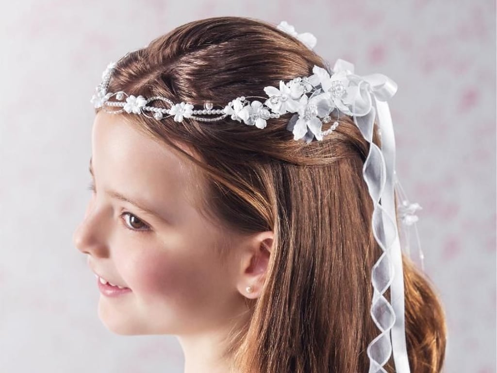 Sind die Haare etwas zurückgesteckt, fallen sie dem Kommunionskind am großen Tag nicht störend ins Gesicht - passender Haarschmuck veredelt den Look. Foto: Emmerling