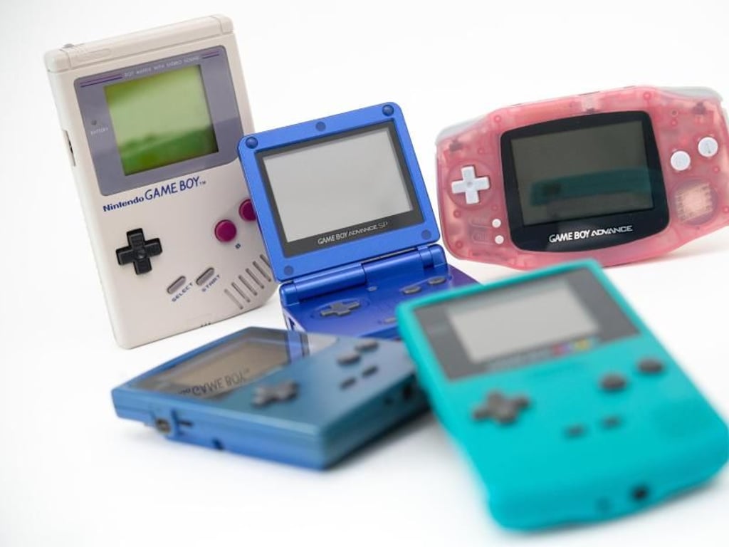 Der erste Game Boy (l in Grau) erhielt über die Jahre etliche Nachfolger wie den Game Boy Pocket (blau, liegend), den Game Boy Advance SP (Mitte, aufgeklappt), den Game Boy Advance (r, rosa) und den Game Boy Color (vorne, mit Farbdisplay). Foto: Andrea Warnecke
