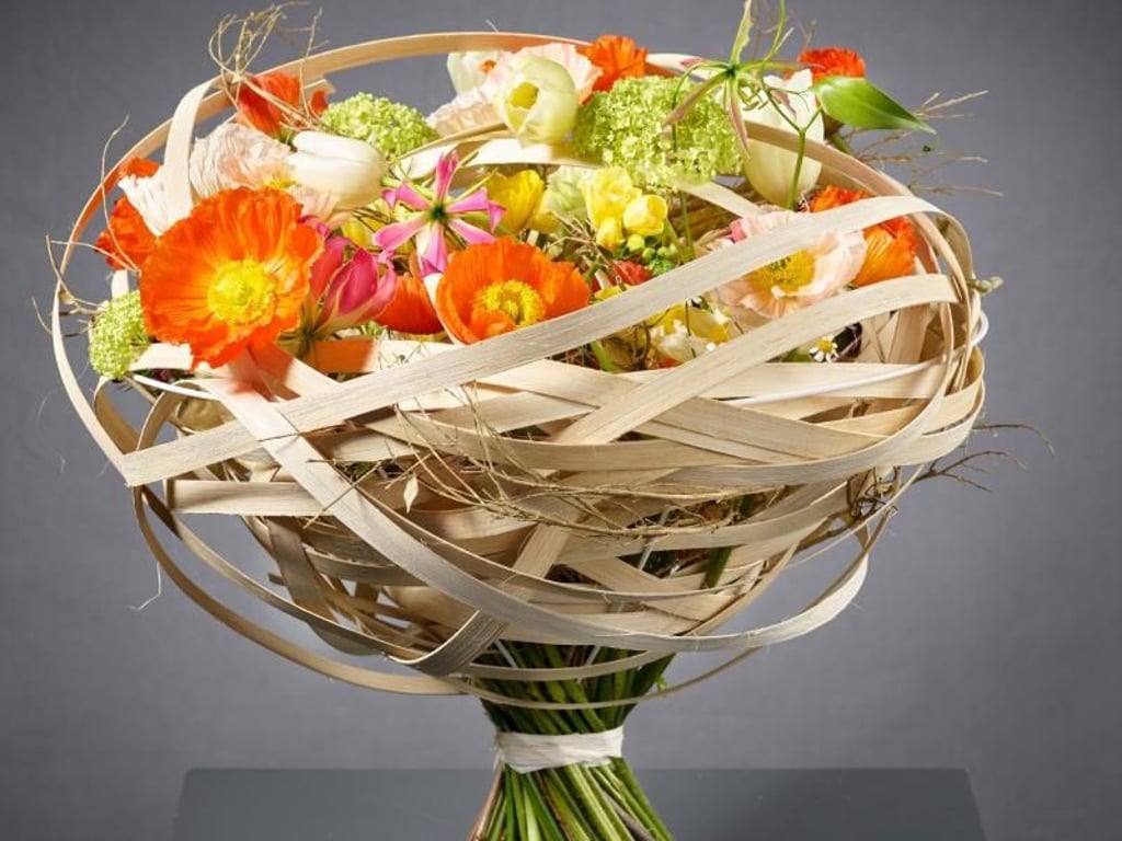 Die roten Mohnblüten sind der Hingucker in diesem Osterstrauß. Eingebettet sind die Blumen in eine Art Nest. Foto: Fachverband Deutscher Floristen e.V./J. Manegold