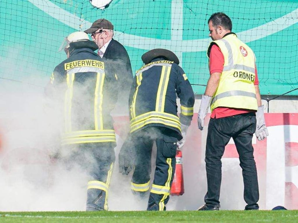 Feuerwehrleute löschen Bengalos aus dem Mainzer Fanblock. Foto: Uwe Anspach
