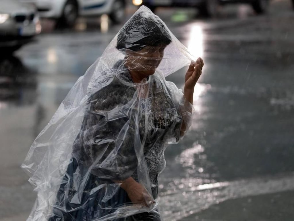 Eine Touristin mit Regencape am Checkpoint Charlie in Berlin. Foto: Kay Nietfeld