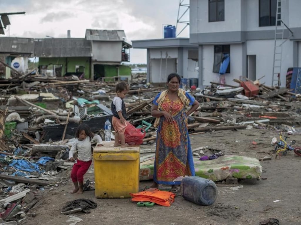Eine Frau und ihre Kinder stehen zwischen Trümmern. Foto: Fauzy Chaniago/AP