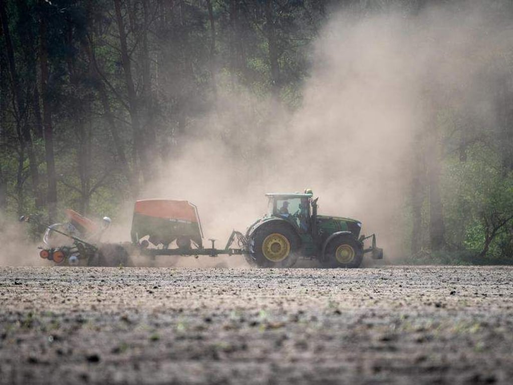 Ein Landwirt fährt mit einer Sämaschine am Traktor über ein trockenes Feld und zieht eine Staubwolke hinter sich her. Foto:&nbsp;Monika Skolimowska