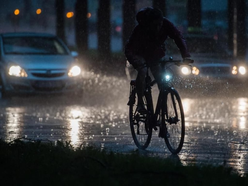 Ein Fahrradfahrer und Autos fahren bei einem Unwetter mit Starkregen. Foto: Silas Stein