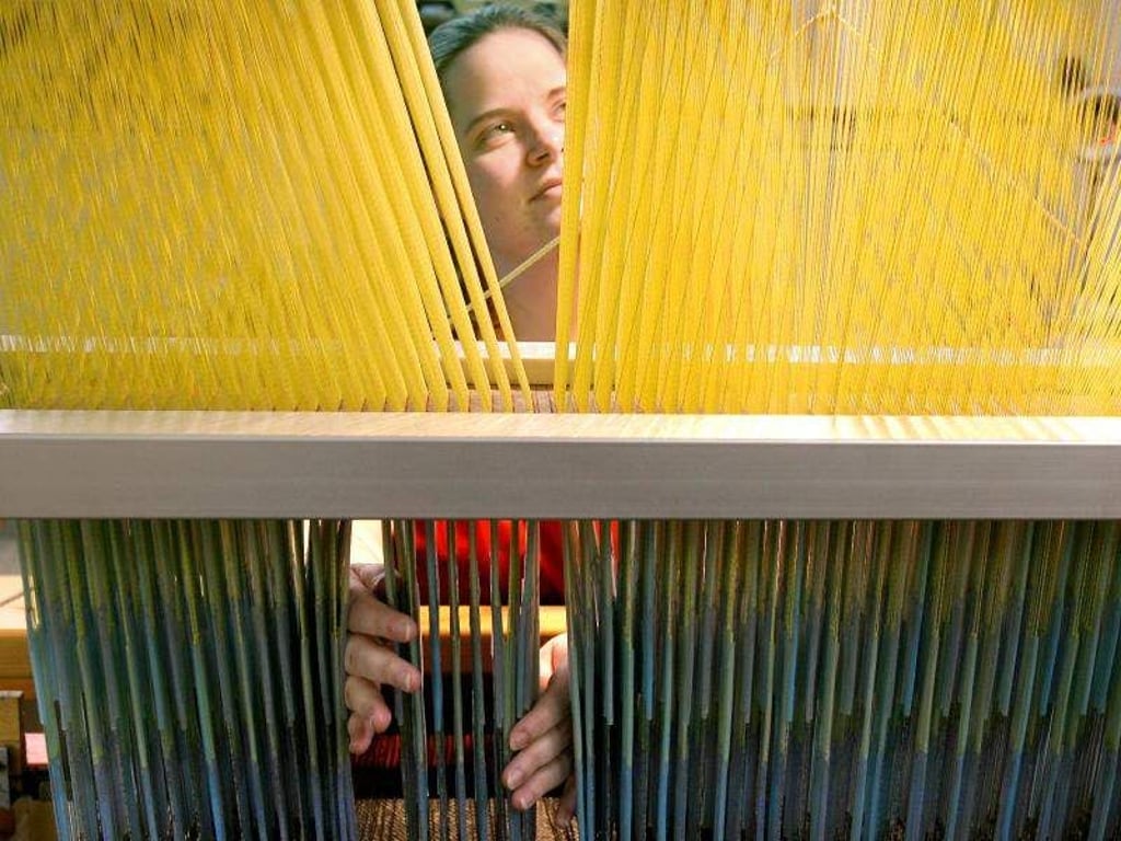 Eine Webergesellin arbeitet an einem Webstuhl. Foto: Waltraud Grubitzsch/Archiv