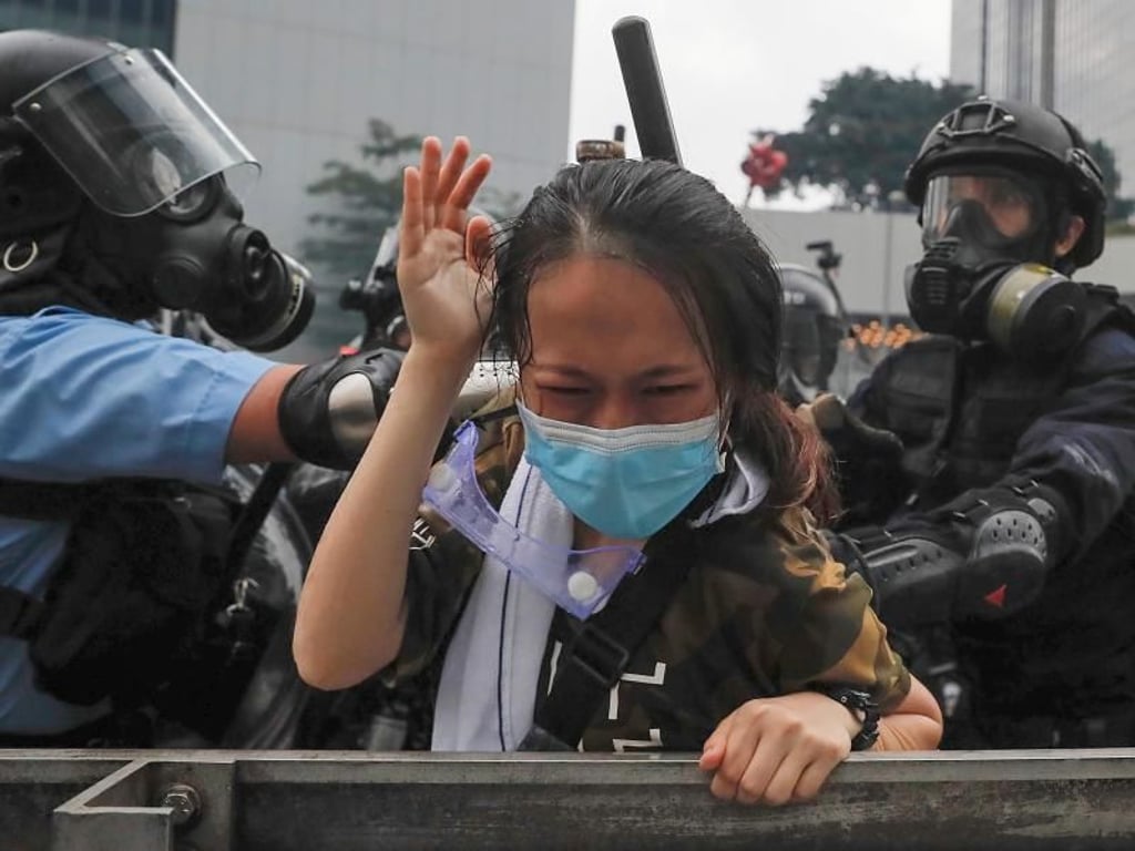 Polizisten drücken eine Demonstrantin gegen eine Absperrung. Foto: Kin Cheung/AP
