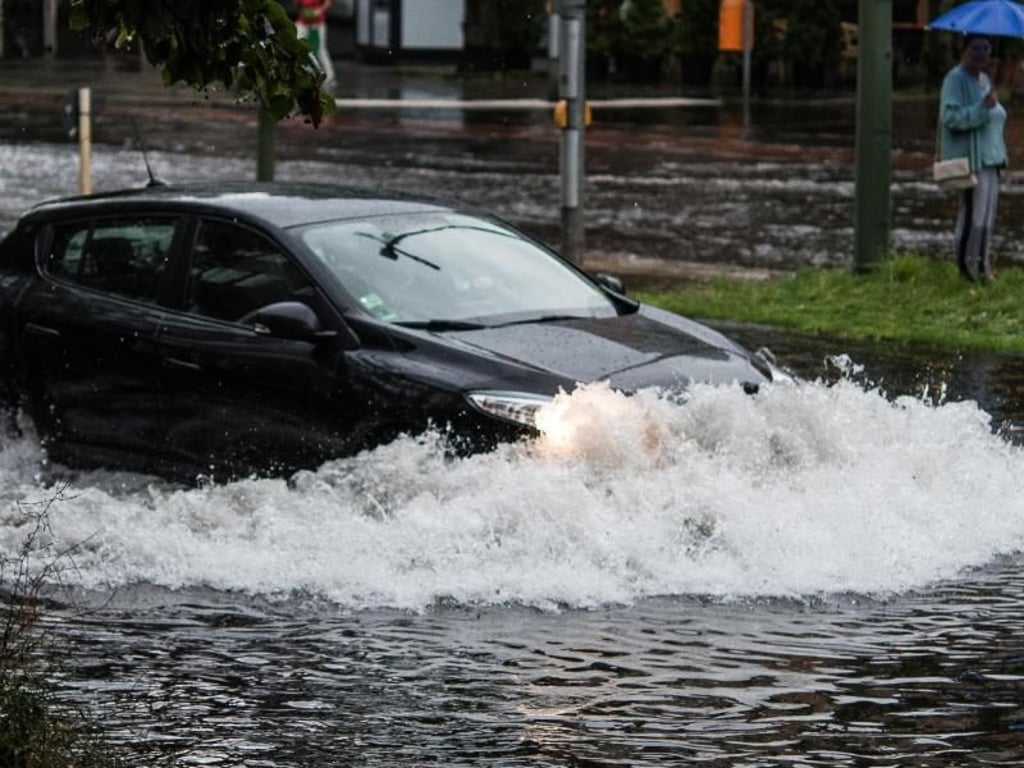 Ein Pkw pflügt sich in Berlin durch die Wassermassen. Foto: Paul Zinken
