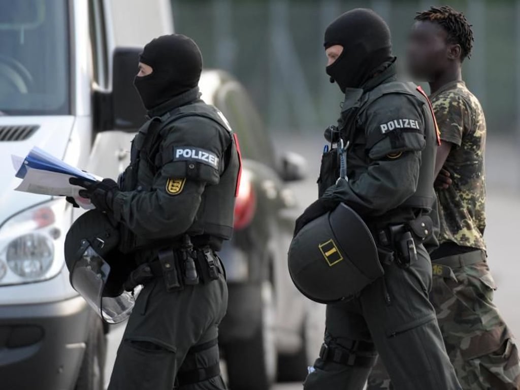 Bei der Großrazzia in der Flüchtlingsunterkunft in Ellwangen wird Flüchtling von Polizisten eskortiert. Foto: Stefan Puchner