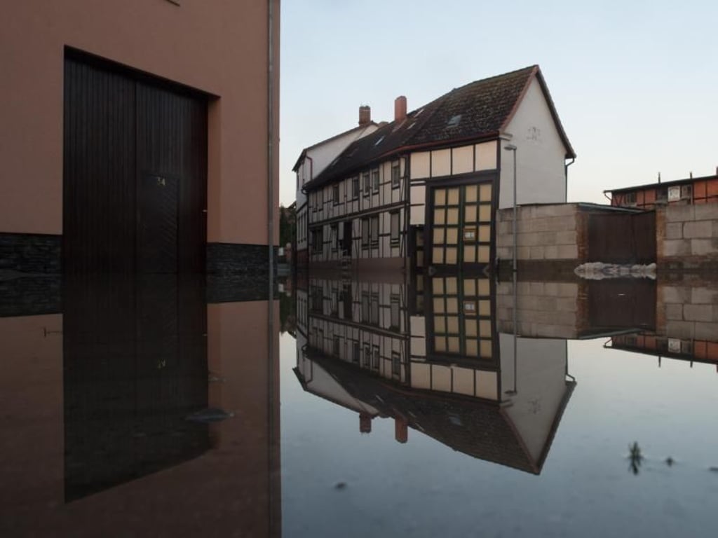 Häuser spiegeln sich in Harsleben (Sachsen-Anhalt) im Wasser der überfluteten Straßen. Foto: Klaus-Dietmar Gabbert