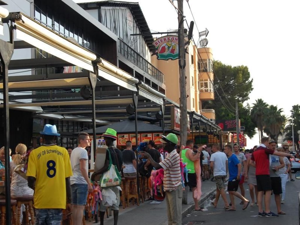 Touristen und Straßenhändler vor dem Bierkönig in Playa de Palma auf Mallorca. Foto: Patrick Schirmer