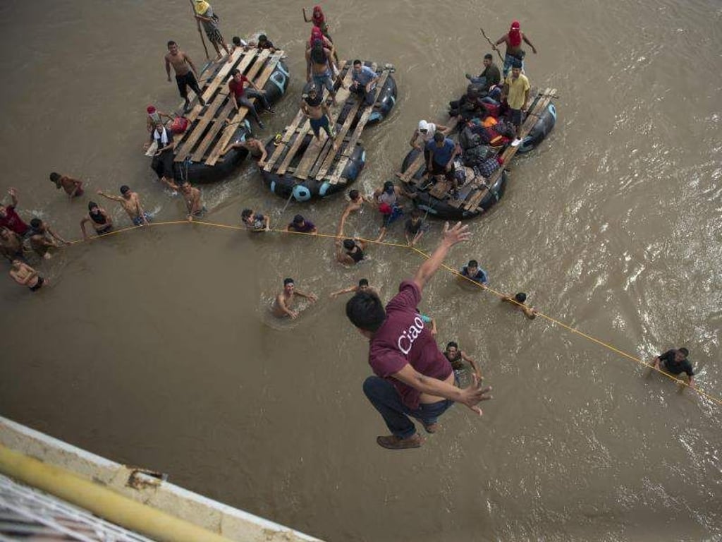 Ein honduranischer Migrant springt von einer Brücke in den Grenzfluss Suchiate. Foto: Oliver De Ros/AP