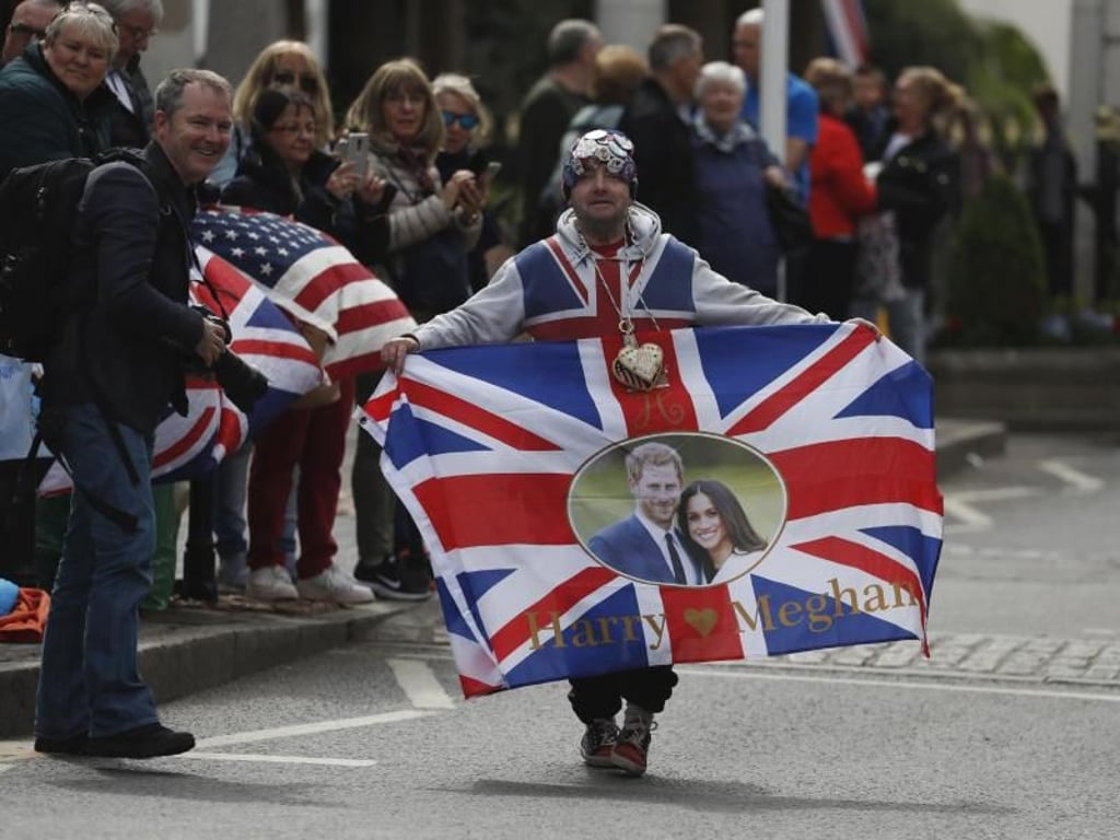 Ein Fan der Königsfamilie mit Union Jack und einem Bild von Prinz Harry und Meghan. Foto: Alastair Grant