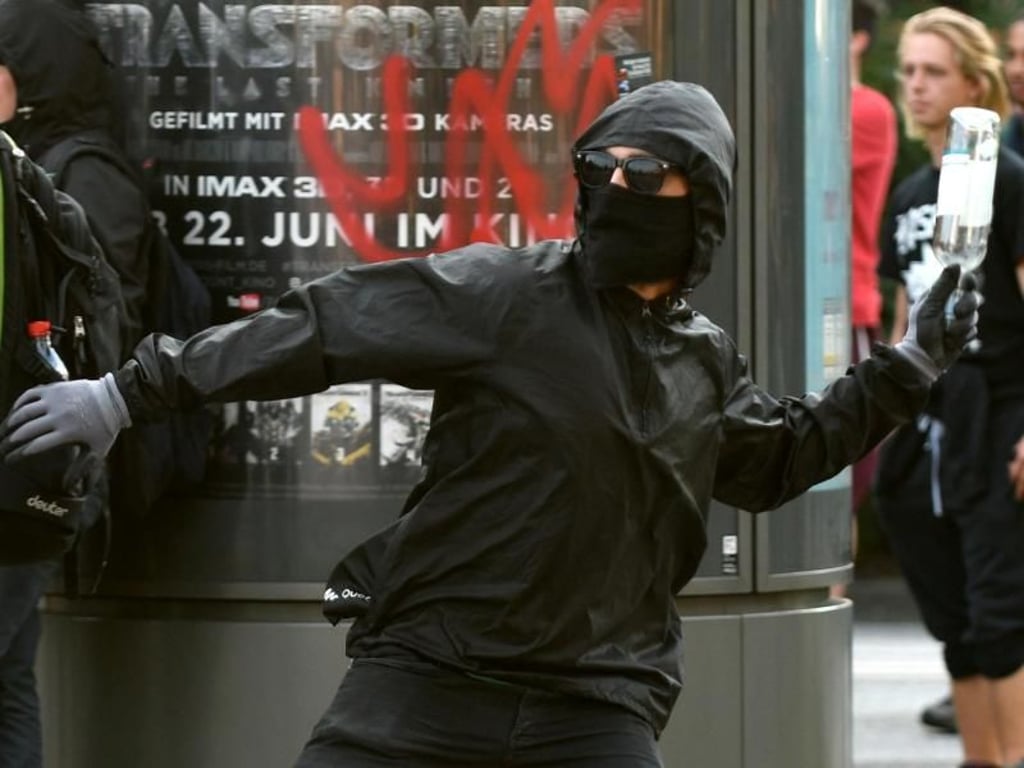 Ein vermummter Randalierer wirft eine Flasche auf Polizisten. Die Union fordert eine «europäische Extremistendatei für Linksradikale». Foto: Axel Heimken