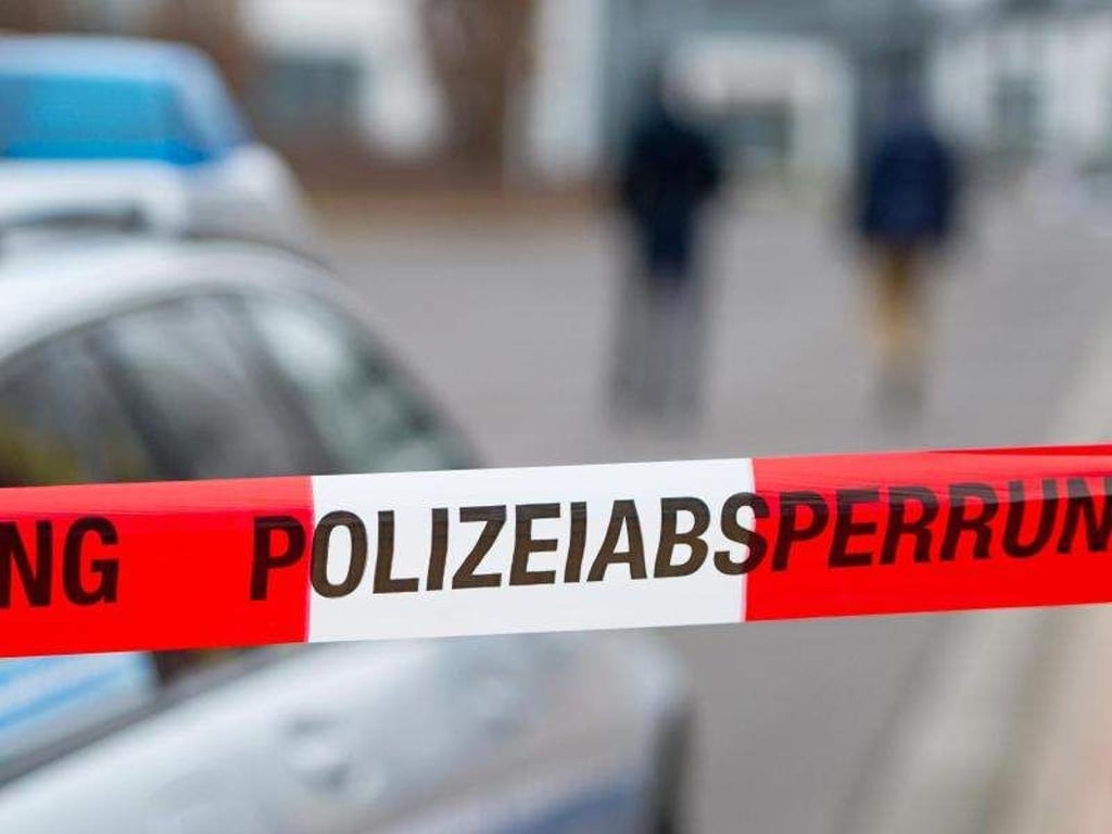 Ein Polizeiabsperrband ist vor einem Polizeiwagen zu sehen. Foto: Marc Tirl/Archiv