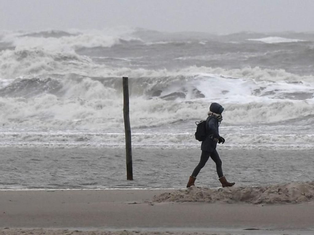 Eine Spaziergängerin geht im Sturm über den Nordseestrand. An der Küste wird eine Sturmflut erwartet. Foto: Carsten Rehder