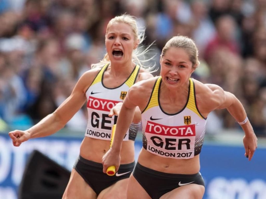 Gina Lückenkemper (l) und Rebekka Haase wechseln im Vorlauf der 4x100 Meter Staffel. Foto: Bernd Thissen