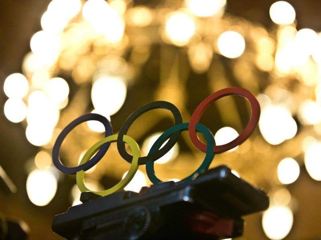 Olympische Ringe aus Holz stehen auf einem Kamerastativ. Foto: Christian Charisius/dpa/Archiv