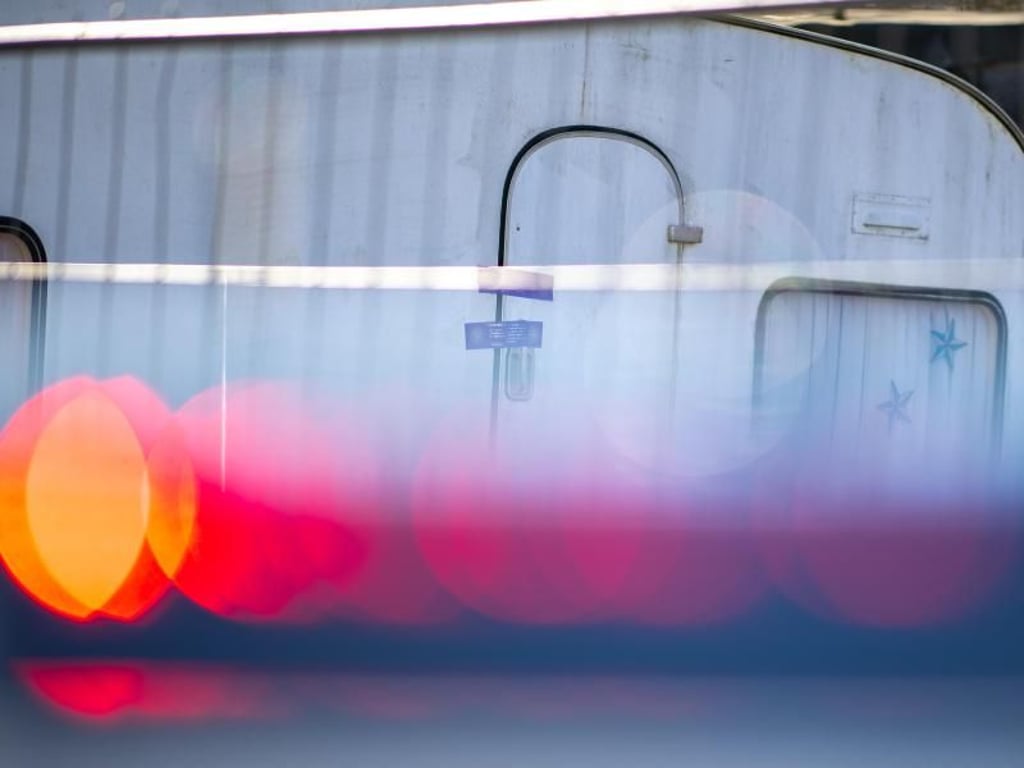 Ein Polizeiauto steht vor dem versiegelten Campingwagen des mutmaßlichen Täters. Foto: Guido Kirchner